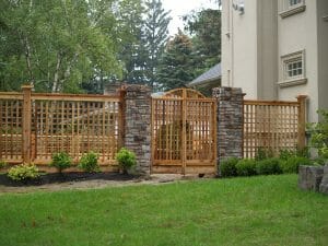 A trelliswork fence with lattice gates and stone posts.